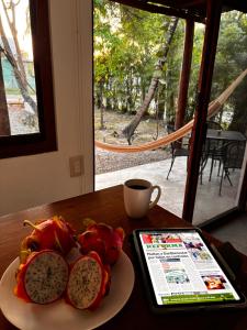 a plate of fruit on a table with a cup of coffee at Tropical Garden Suites steps from the Lagoon in Bacalar
