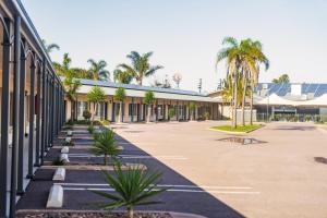a building with a lot of palm trees in a parking lot at Sundowner Motel Hotel in Whyalla