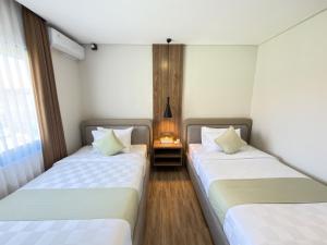 two beds in a room with a lamp between them at Kana Suites Nusa Dua By Fays Hospitality in Nusa Dua +24 photos