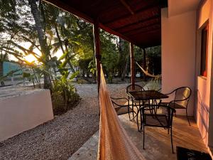 a hammock outside of a house with a table and chairs at Tropical Garden Suites steps from the Lagoon in Bacalar