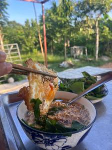 a bowl of food with a piece of meat and noodles at Cat Tien Riverside Lodge in Tân Phú