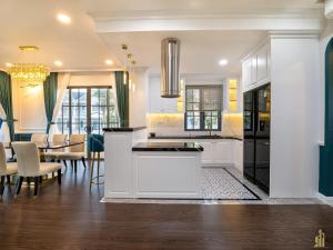 a kitchen with white cabinets and a dining room at Villa Malibu Phan Thiet, Free Parking in Phan Thiet