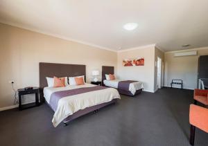 a hotel room with two beds and a television at Sundowner Motel Hotel in Whyalla