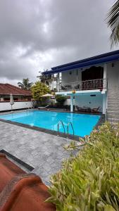 a large swimming pool in front of a house at Chamo Villa by DrMocktail in Beruwala
