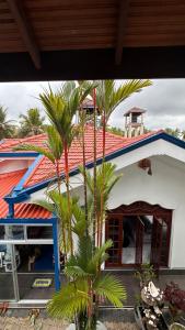 a house with a palm tree in front of it at Chamo Villa by DrMocktail in Beruwala