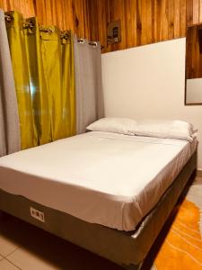 a bed in a room with yellow curtains at Volcano Refuge House in Fortuna