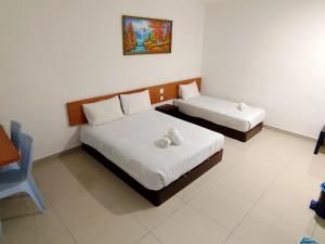 a room with two beds and a chair in it at Aloha Hotel in Lumut +23 photos