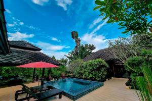a house with a swimming pool and a red umbrella at Villa Khao Phaengma in Wang Nam Khieo