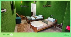 two beds in a room with a green wall at rajapalace in Zahirābād