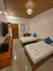 a hotel room with two beds and a television at Beehive El Nido in El Nido