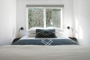 a white bedroom with a bed with a window at Cedar Lodge in Braidwood