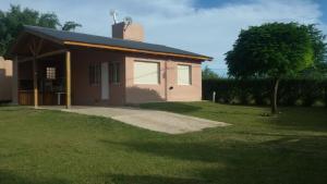 una pequeña casa en un campo con un patio de césped en Cabañas Cuncumen en Los Reartes