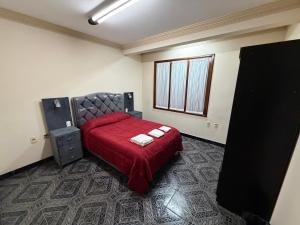 a bedroom with a bed with a red bedspread at Altos de Belgrano Suites in Tarija +3 photos