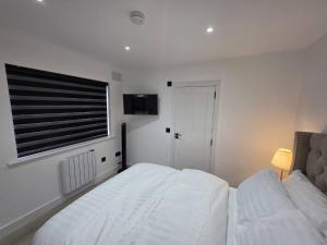 a white bedroom with a bed and a window at Luaz - View Lodge in Dublin