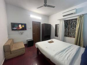 a bedroom with a bed and a tv and a chair at Hotel White Sand Bache Stay in Aguada