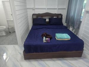 a bed with a blue comforter and a bottle and towels at sabai resort in Pattaya South