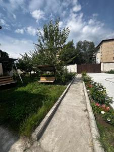 a garden with a park bench and a sidewalk at Aida in Tebykty +1 photo