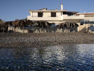 a house on the beach with a body of water at Athanasia Villa in Nerátza