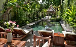 a swimming pool in a garden with chairs and a table at The Tree - Adults only in Siem Reap