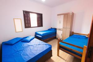 a bedroom with two beds and a cabinet at Sinuca, churrasqueira e fogueira a 300 metros do mar in Itanhaém +65 photos