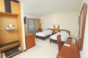 a hotel room with two beds and a desk at Baron Indah Hotel Solo in Grogol