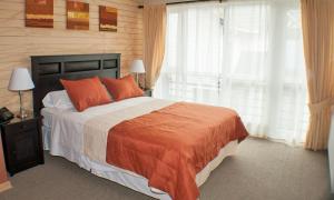 1 dormitorio con 1 cama con almohadas de color naranja y ventana en Madero Aysen ApartHotel en Coyhaique