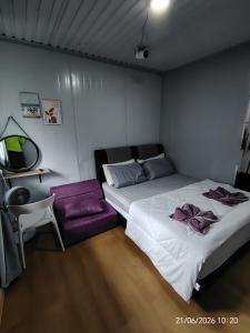 a bedroom with two beds and a purple couch at DMaro Cabin in Kampong Kundassan