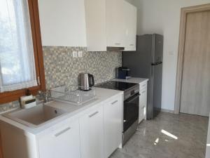 a kitchen with white cabinets and a sink and a refrigerator at ELEVER Apartments in Agia Marina +28 photos