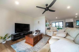 a living room with white furniture and a ceiling fan at Serenity Sands in South Mission Beach
