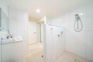 a white bathroom with a shower and a sink at Serenity Sands in South Mission Beach +26 photos