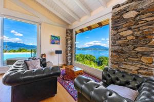 a living room with leather furniture and a large window at Paradis Relais Infinity Pool Lake View in Belgirate