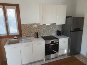 a kitchen with white cabinets and a stove and refrigerator at ELEVER Apartments in Agia Marina