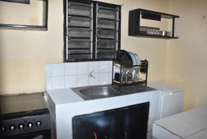 a kitchen with a sink and a stove at Maya Homestay in Ukunda