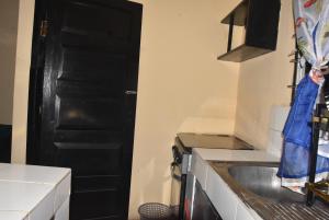 a kitchen with a black door and a sink at Maya Homestay in Ukunda +1 photo