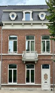 a red brick building with white windows and a balcony at Elegant Manor House in Tongeren