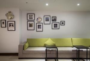 a living room with a green couch and pictures on the wall at Wemeet Hotel in Pingtung City