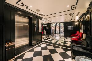 a lobby with a checkered floor and red chairs at Bay Luxury Fortune Grand Hotel in Hanoi