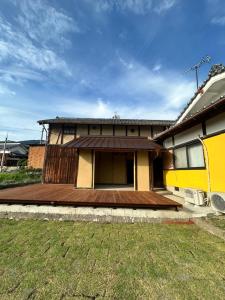 a house with a wooden deck in the yard at よんなーハウス in Kameoka
