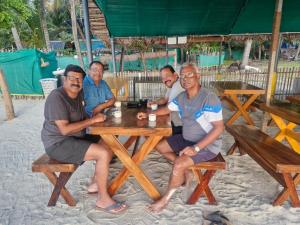 a group of men sitting at a picnic table on the beach at La Paraso Agatti in Agatti