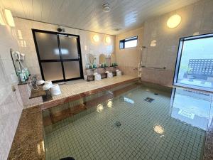 a large bathroom with a shower and a sink at Hotel Route-Inn Niihama in Niihama