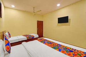 a bedroom with two beds and a flat screen tv at FabHotel Prime Nakshatra Inn in Hyderabad