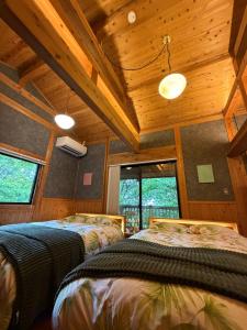 two beds in a room with wooden ceilings and windows at 森権太 Forest Gonta in Takamori
