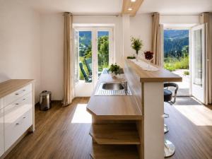a kitchen with a sink and a counter with a window at Apartmenthaus Ahorn in Mittelberg