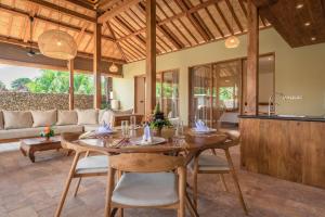 a dining room with a table and a couch at Villa Danginan & Dajanan Pemuteran in Pemuteran