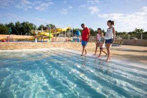 a group of people standing in the water at a pool at Mobil home 3ch, clim, bord de mer in Seignosse