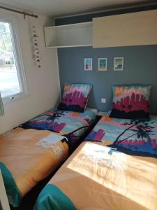 two beds sitting next to each other in a room at Mobil home 3ch, clim, bord de mer in Seignosse