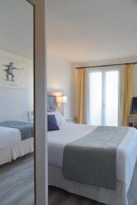 a bedroom with two beds and a large window at Hôtel Les Comtes de Pardiac in Marciac
