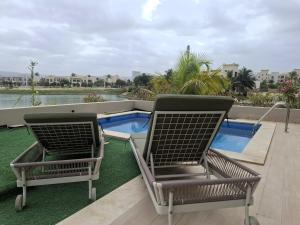 two chairs sitting on a balcony with a swimming pool at Tulip River View in Ma‘mūrah