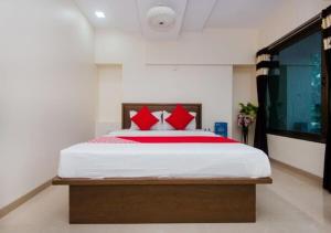 a bedroom with a large bed with red pillows at Hotel Cliff Hanger in Mumbai