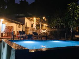 a swimming pool in front of a house at night at The Nook in Deraniyagala